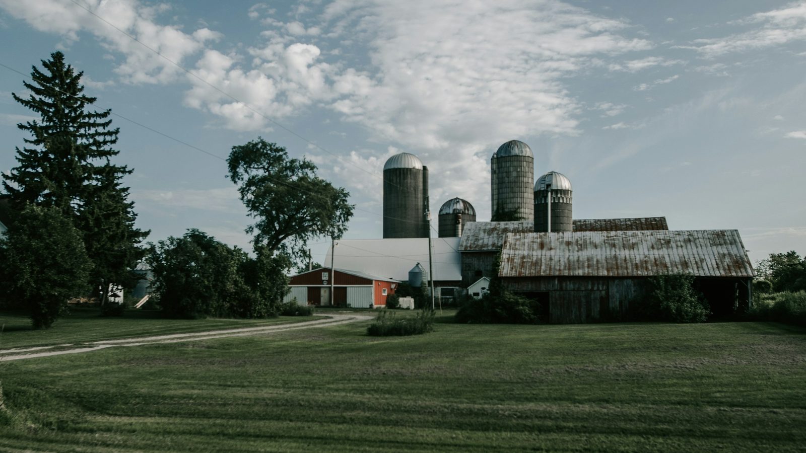 Wisconsin farm with a red barn, metal-roofed barns and silos behind a mowed lawn